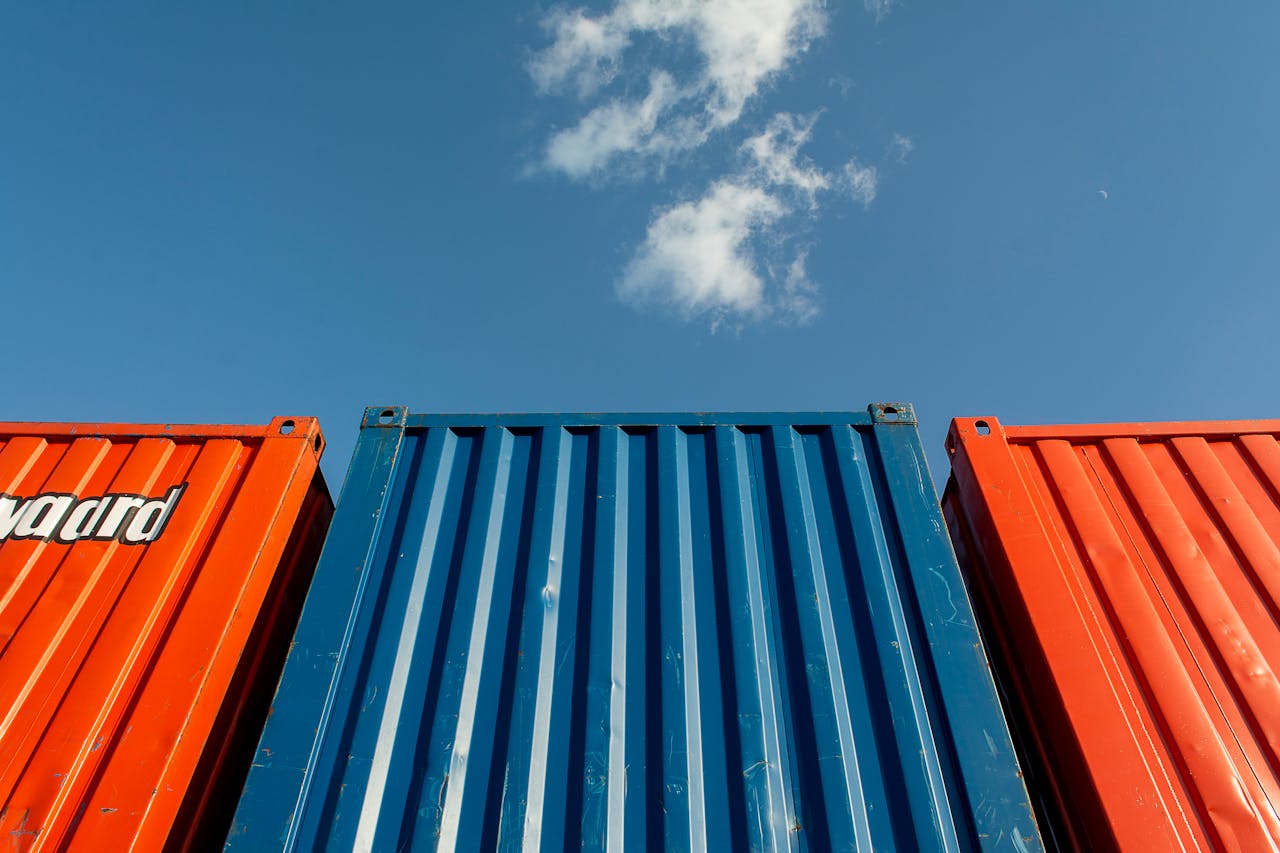 services-04 Vibrant red and blue shipping containers under a clear sky, perfect for industrial themes.