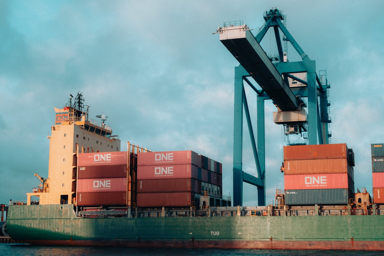 Large cargo ship loaded with colorful containers at a bustling industrial port.